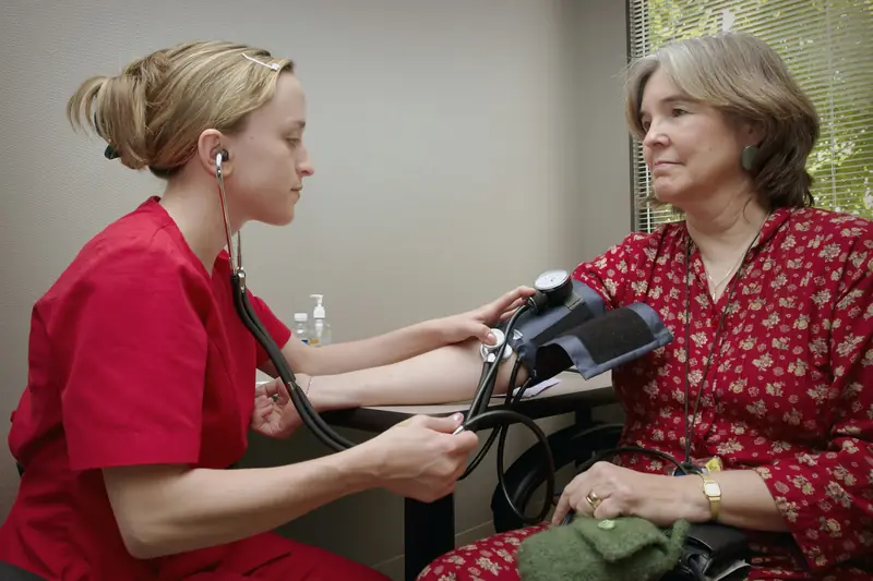 A nurse checking an older woman’s blood pressure at home